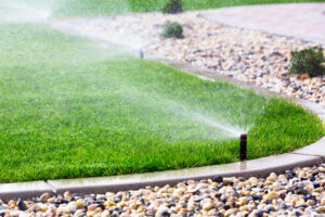 sprinkler system watering a lawn with stone garden in the foreground