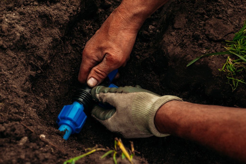 A person shutting off the main valve for their sprinkler system