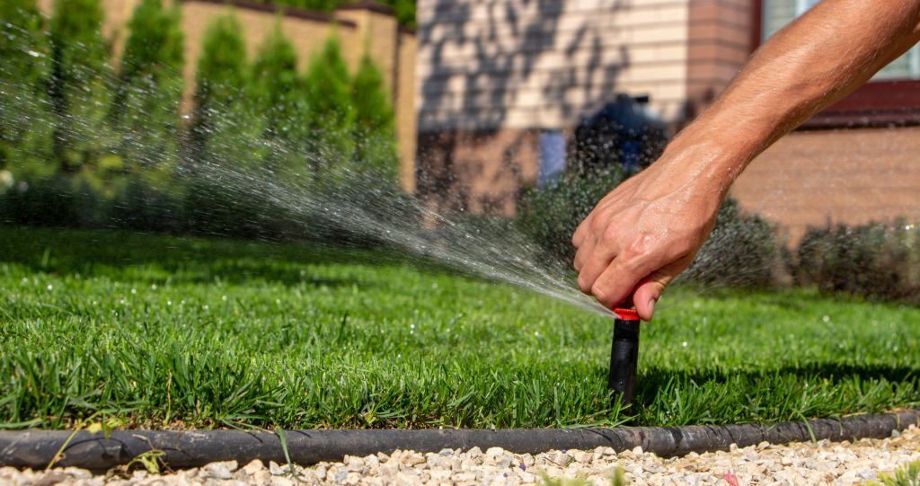 An expert adjusting a sprinkler for proper watering.