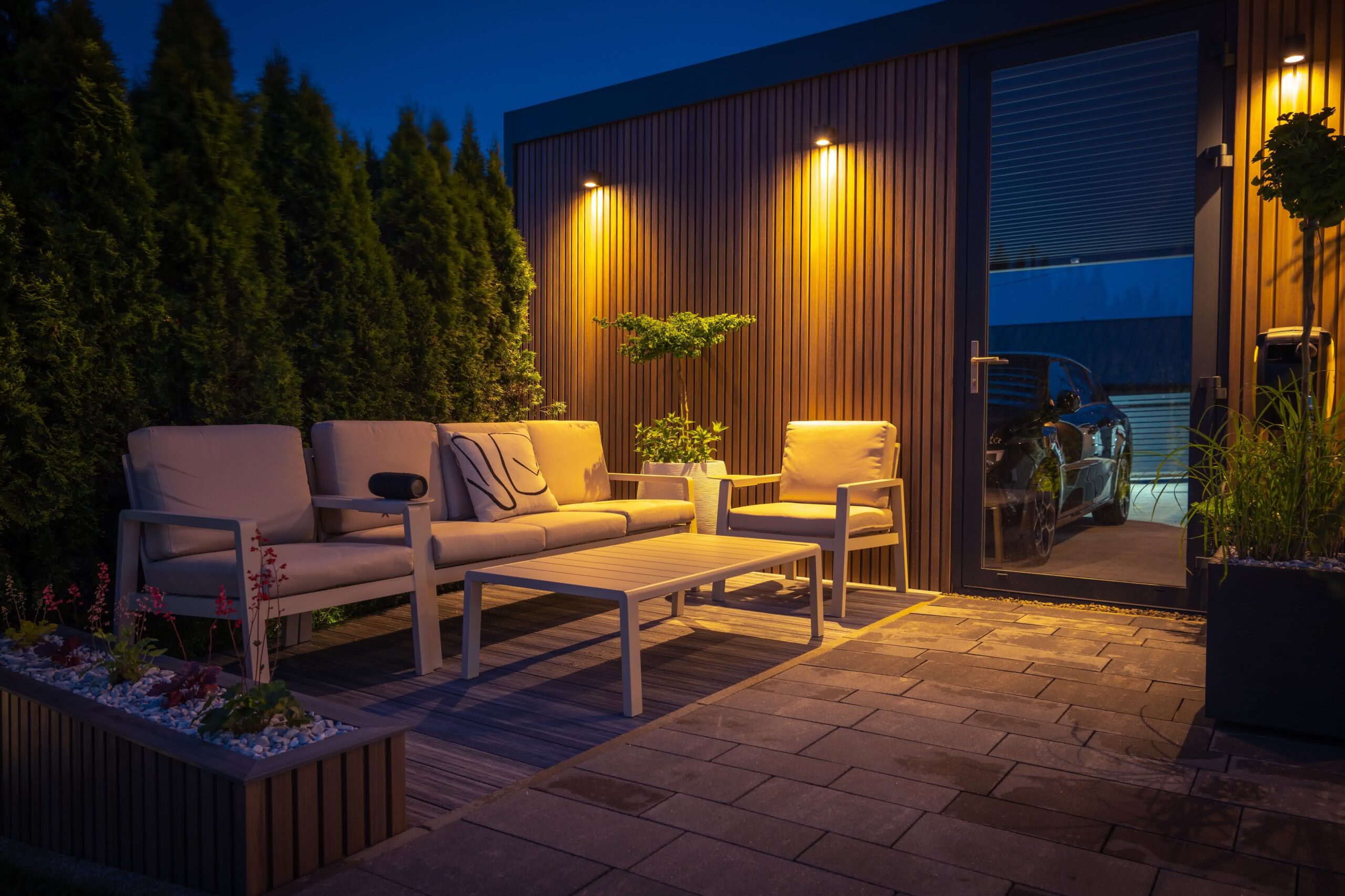A cozy outdoor living area with warm overhead lights and a nice furniture section.