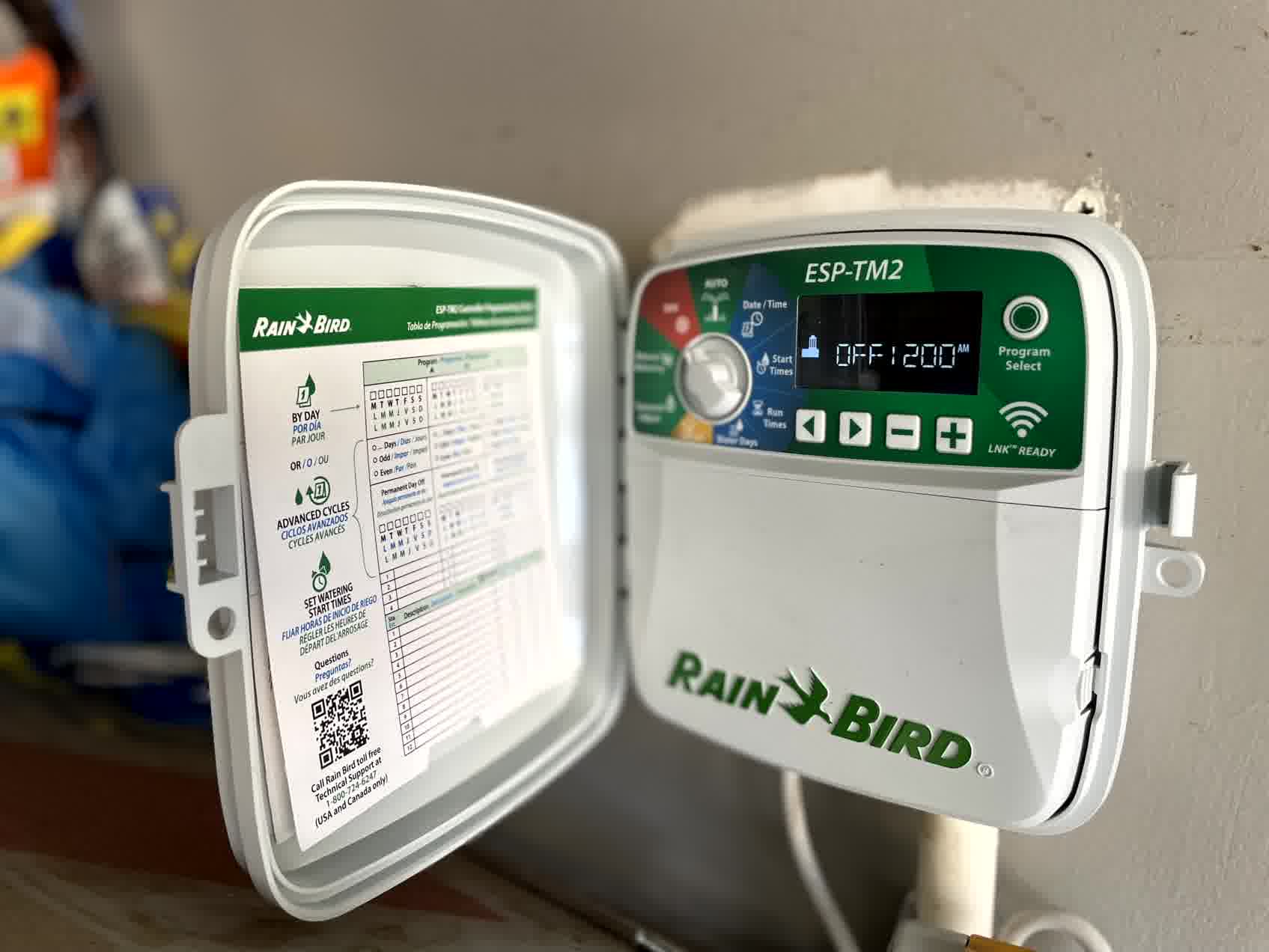 Rain Bird irrigation controller with programming guide open, ready for scheduling lawn watering cycles for efficient landscape care.