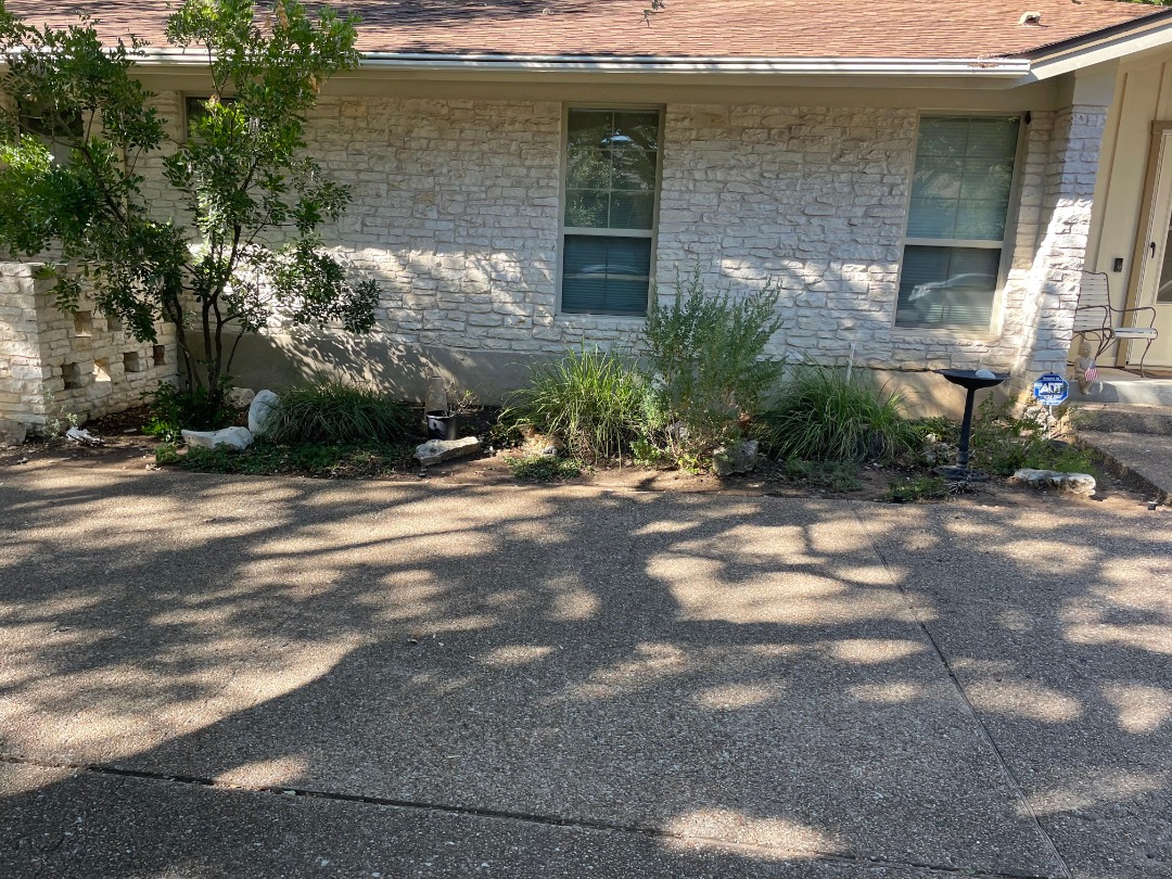 Front yard outdoor living space ready for landscape transformation, featuring shaded areas and planting beds.