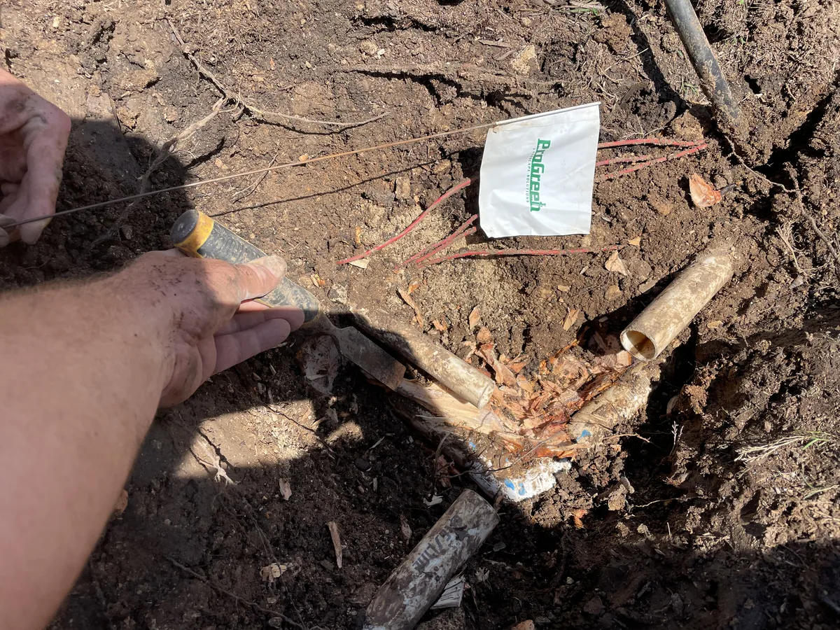 Irrigation inspection in progress with valve locator scanning underground system beside ProGreen marker flag.